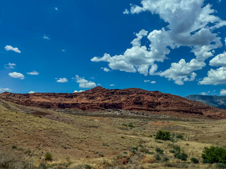 desert landscape with red rock mountain against blue cloudy sky, copy space