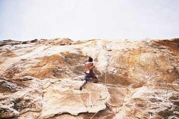 Rock climbing, mountain and man in nature for sport, fitness or adventure on cliff. Rope, explore or safety with harness and equipment for male person, hobby or rocks for challenge on boulder outside