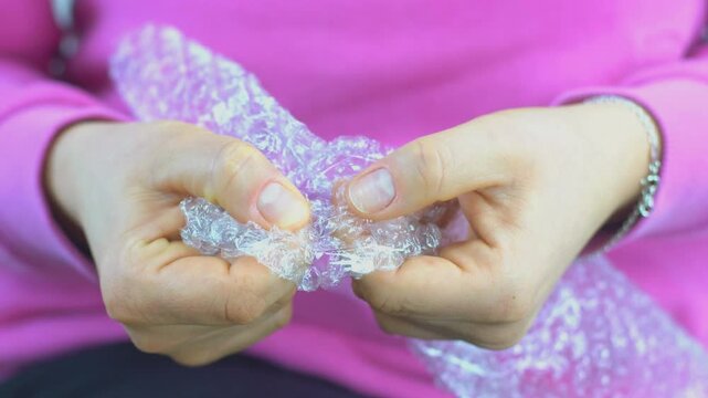 Woman pops plastic bubble wrap, Nervous person popping bubble wrap as a stress relief.
