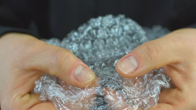 Woman pops plastic bubble wrap, Nervous person popping bubble wrap as a stress relief.
