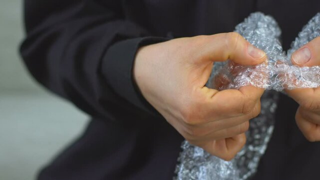 Woman pops plastic bubble wrap, Nervous person popping bubble wrap as a stress relief.
