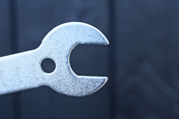 part one gray metal wrench on black background
