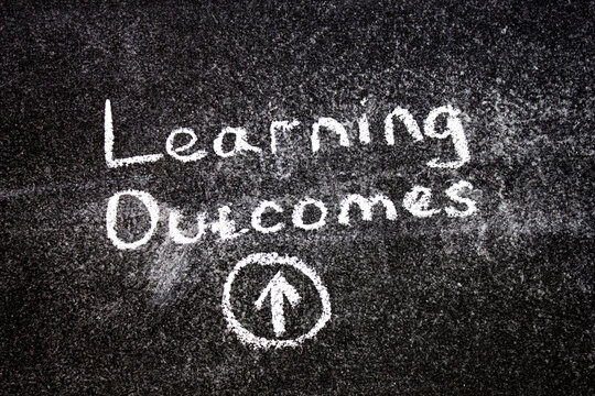 LEARNING OUTCOMES text, chalk on the board. Learning Outcomes educational concept.