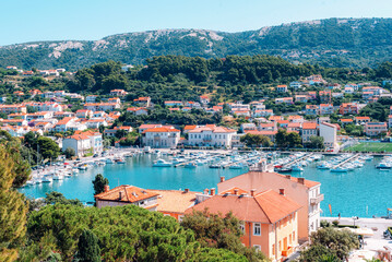 Panoramic view of Rab town with red tiled roofs and mountains on horizon. Rab island, Croatia