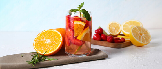 Glass of fresh infused water with strawberries and different citrus fruits on white table