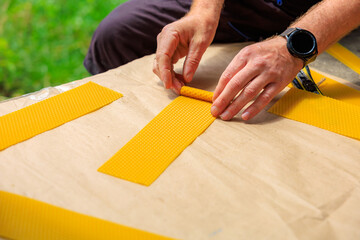 A man rolls decorative candle made of natural beeswax