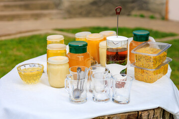 Natural products of beekeeper farmer including different types of honey, pollen and propolis on the table and cups