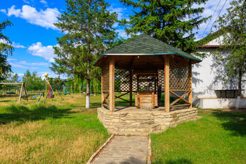 A wooden pavilion with a roof and a small table, rural well