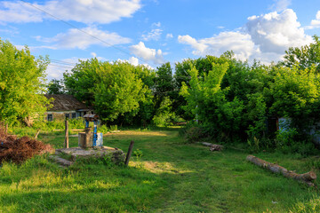 A small house sits in a grassy field with a well in the middle