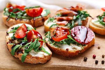 Wooden board of tasty sandwiches with cream cheese, arugula and tomatoes, closeup