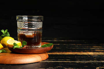 Glass of rum with lime on dark wooden background