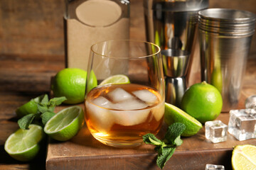 Glass of rum with ice, mint and lime on wooden table