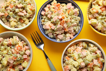 Bowls of tasty Olivier salad on yellow background