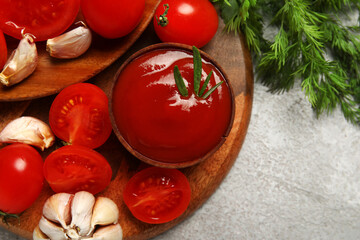 Bowl with tasty ketchup and fresh vegetables on light background, closeup