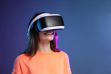 Smiling woman using virtual reality headset on dark blue background. Space for text