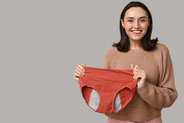 Beautiful young woman with period panties on grey background