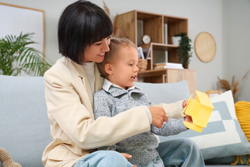 Obraz premium Young mother and her little son playing with toy airplane at home