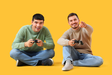 Young brothers playing video games on yellow background
