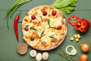 Board with tasty pizza and ingredients on green wooden background