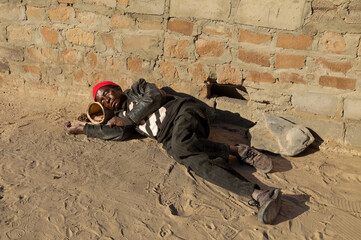 old African man sleeping on a dirt road in the city, village, alcoholism and drug addiction