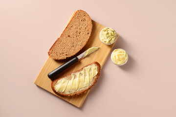 Wooden board with bread slices and bowls of fresh butter on brown background
