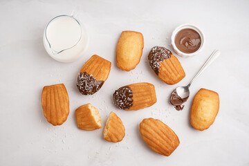 Delicious madeleines, spoon and bowl with chocolate cream on white background