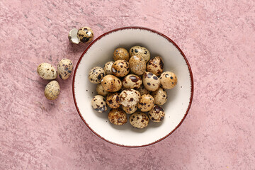 Bowl with quail eggs on pink grunge background