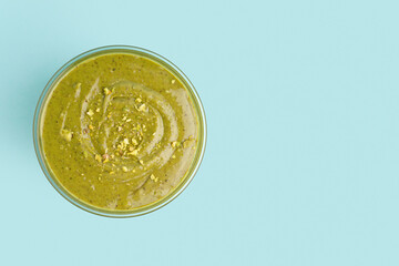 Tasty pistachio paste in bowl on blue background