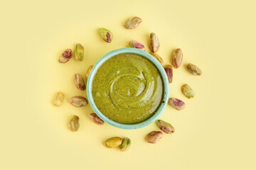 Bowl with tasty pistachio paste on yellow background