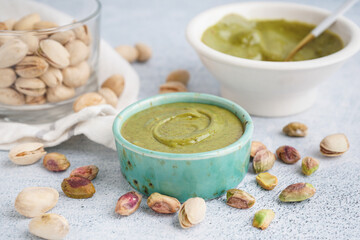 Bowls with tasty pistachio paste on white grunge background