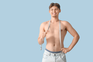 Fototapeta premium Sporty young man with measuring tape on light background. Weight loss concept
