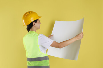 Engineer in hard hat with draft on yellow background