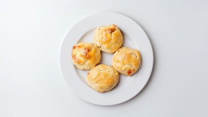 Golden cheese scones on a white plate, freshly baked and ready to serve with a touch of gourmet elegance