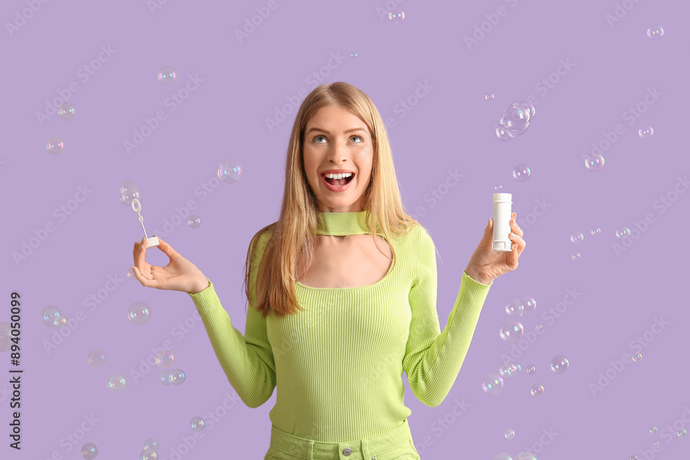 Poster Surprised young woman with soap bubbles on purple background