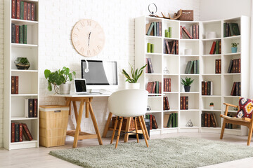 Stylish office with workplace, modern computer, chair and bookcase