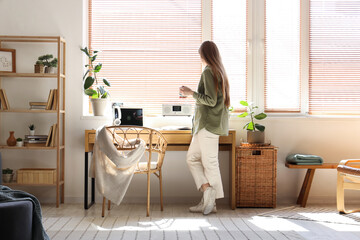 Young woman drinking coffee near workplace in stylish office