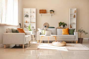 Interior of beautiful living room with grey sofas, houseplants, coffee table and shelving unit