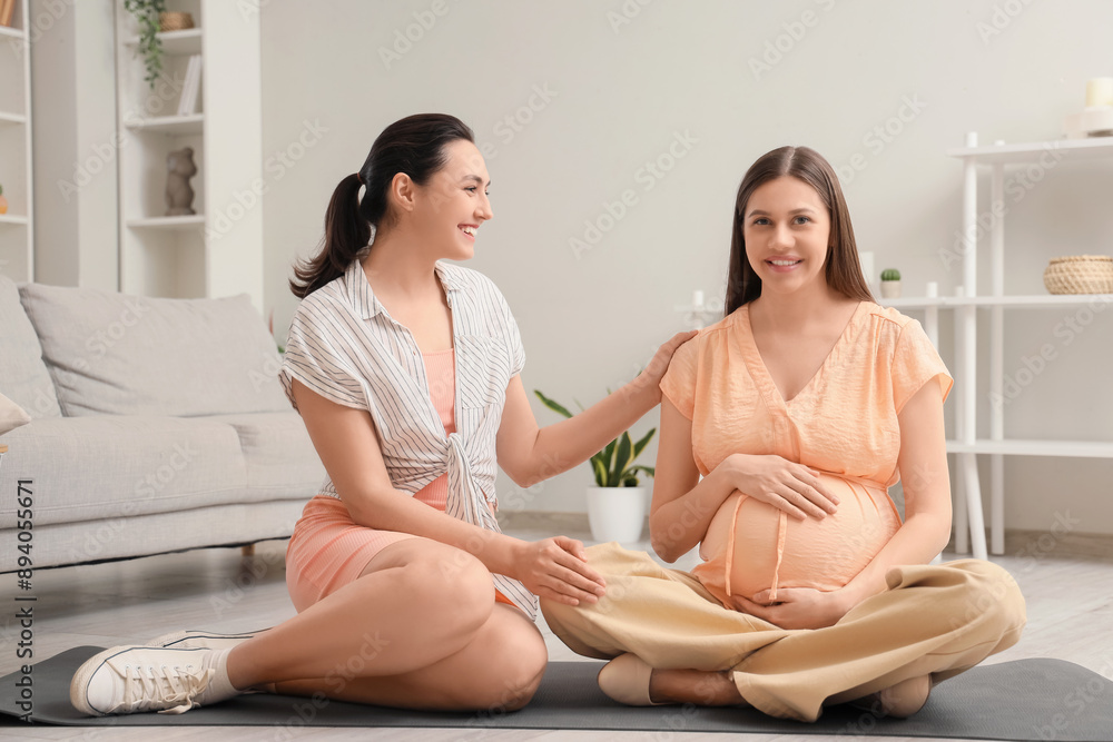 Canvas Prints Young pregnant woman with doula sitting on mat at home