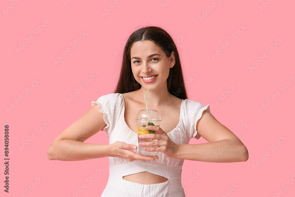 Poster Beautiful young happy woman with cup of fresh lemonade on pink background