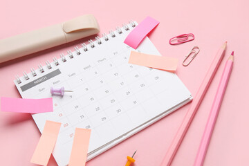 Calendar with office stationery on pink background