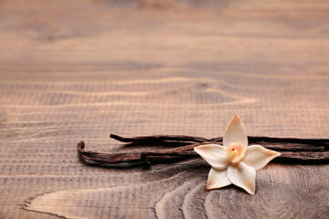 Beautiful vanilla flower and sticks on wooden background