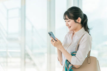 オフィスビルでスマホを使っているアジア人ビジネスウーマン
