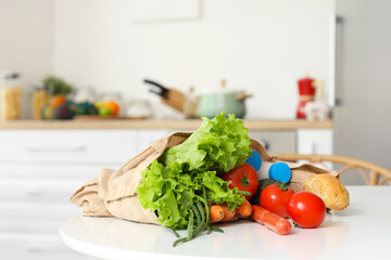 Vegetables, milk and bread in eco bag on table in kitchen