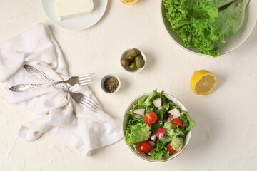 Composition with bowl of healthy salad, ingredients and forks on light background