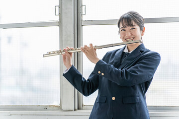 教室でフルートを吹く吹奏楽部のアジア人女子高生  © buritora