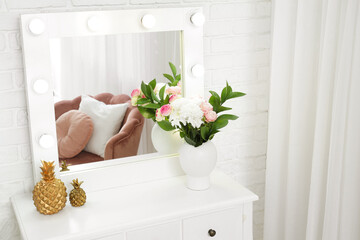 Interior of room with mirror, chest of drawers and vase of flowers, closeup