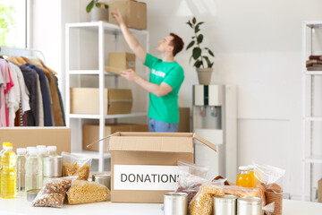Donation box with food on table in volunteer center, closeup