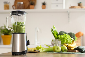 Blender with ingredients for tasty smoothie on table in kitchen