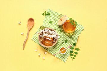 Jars and bowl of sweet honey with acacia flowers on yellow background