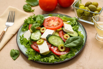 Plate of fresh vegetable salad with fork and ingredients on beige background